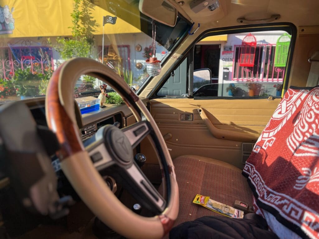 A person driving a vintage car with a wooden steering wheel.