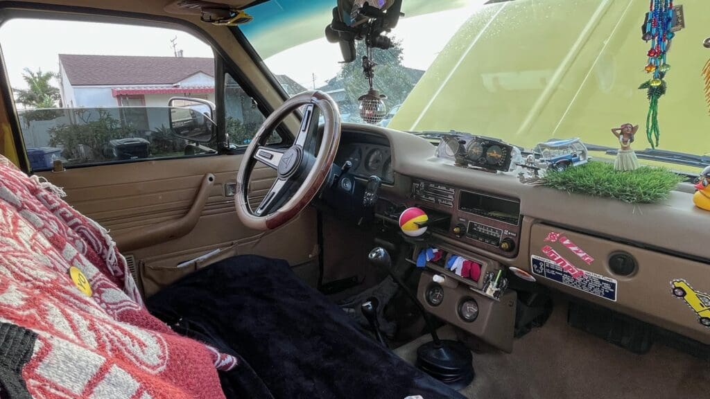 Interior view of a car showing the dashboard and steering wheel with various decorations.