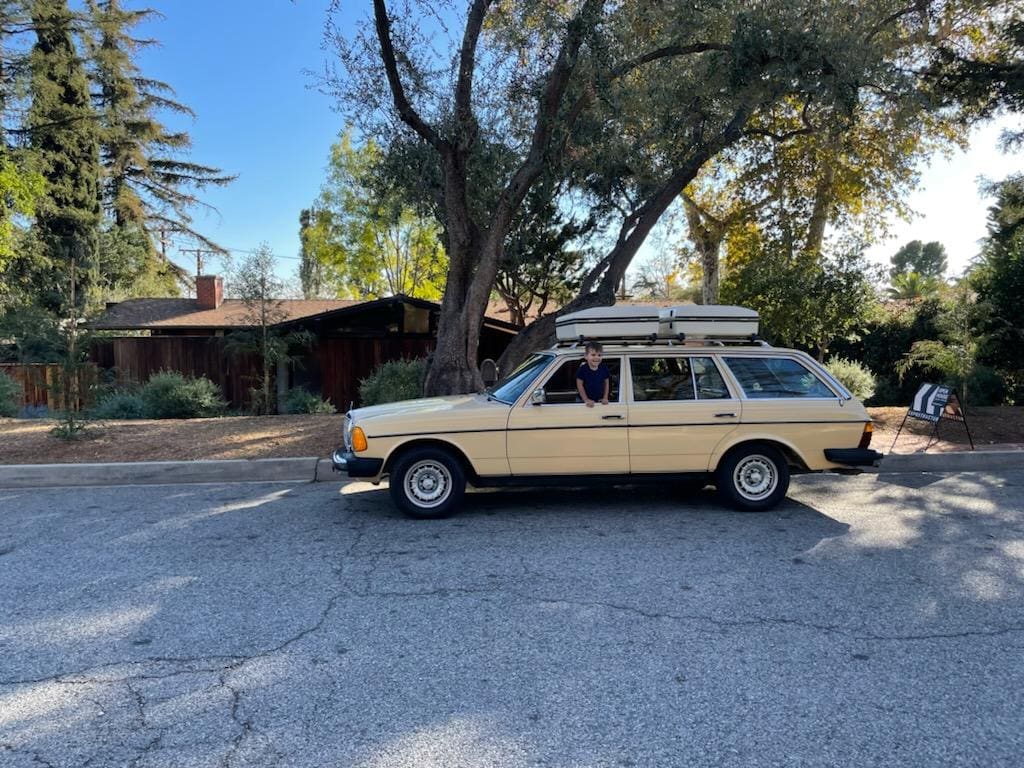 A vintage beige station wagon parked on a sunny street.