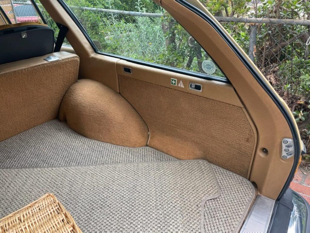 Vintage car trunk with brown upholstery and woven basket.