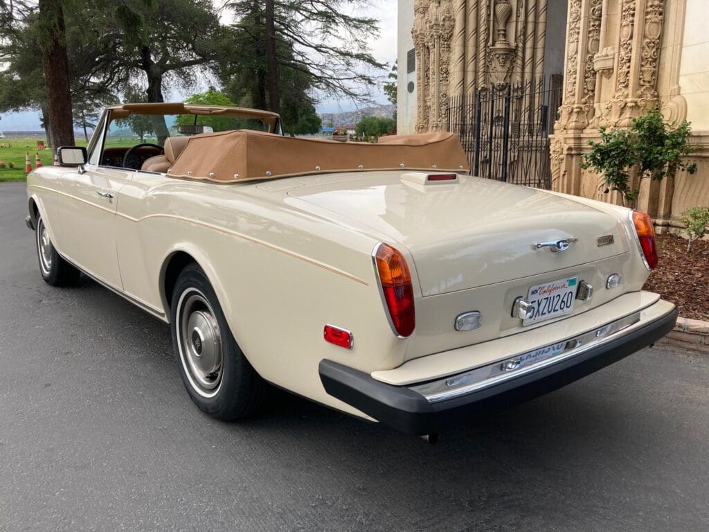 Classic white convertible car parked near a historic building.