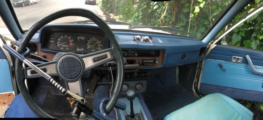 Vintage car interior with blue dashboard and manual gear shift.