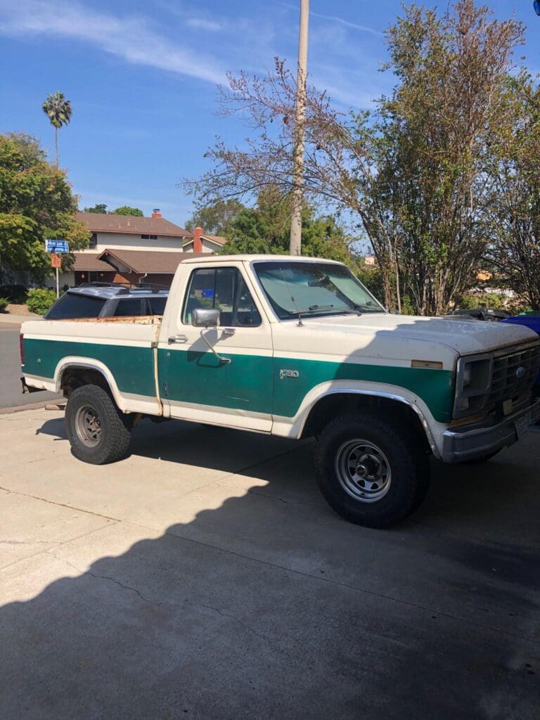 Classic green and white pickup truck parked in a desert landscape.