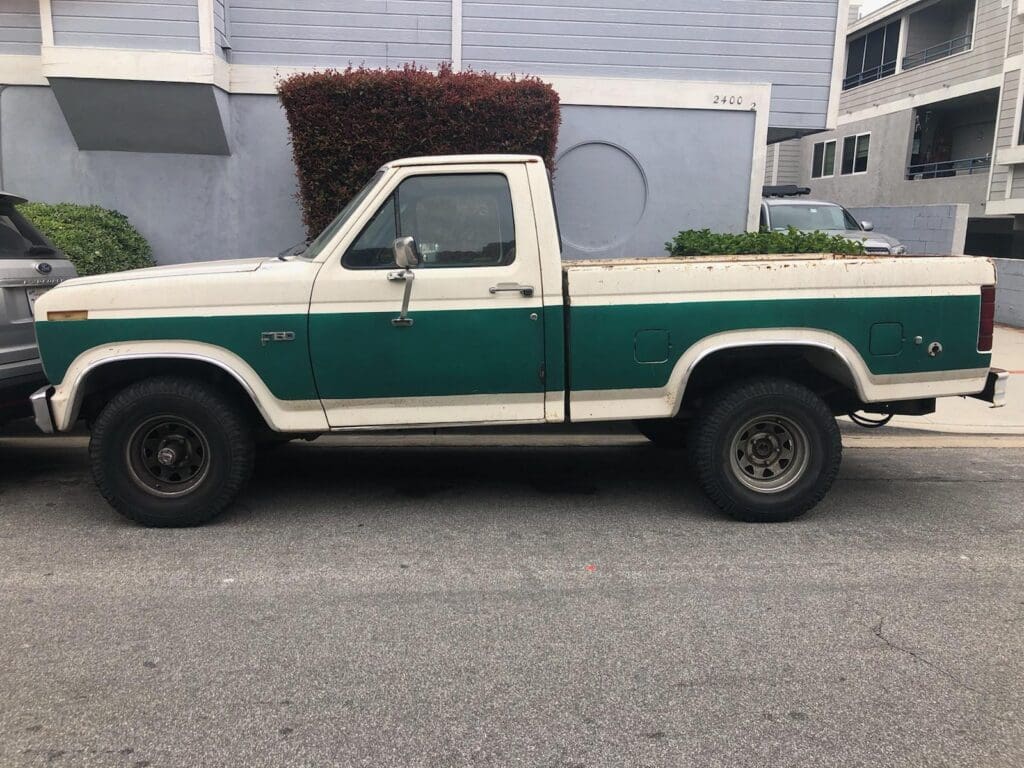 A vintage two-tone green and white pickup truck parked on a street.