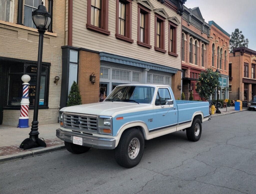 Vintage blue and white pickup truck parked on a city street.