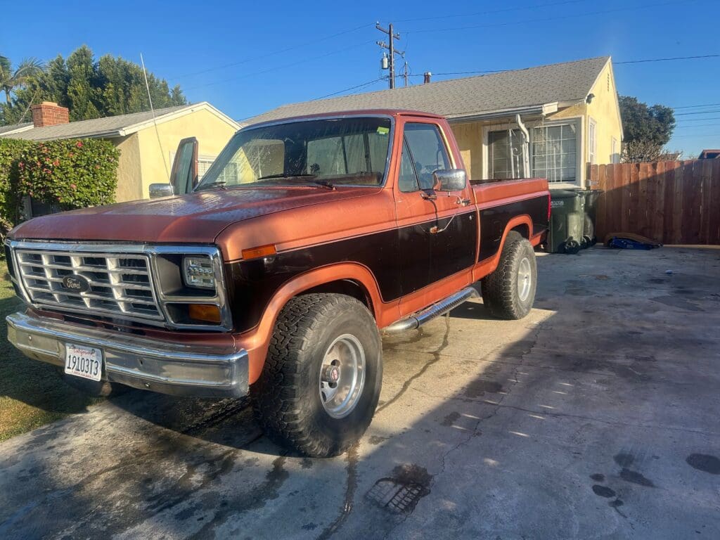 Classic red and black vintage pickup truck parked outside a house.