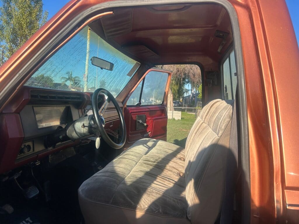 Interior of a vintage truck showing the driver's seat and steering wheel.