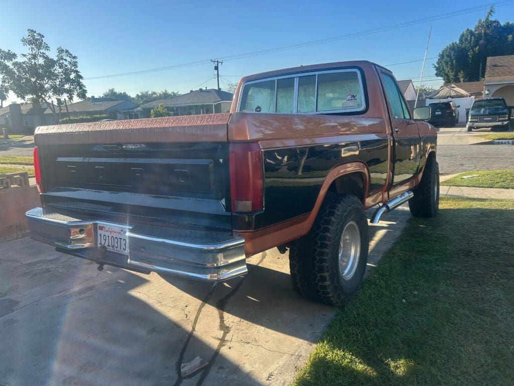 Classic black pickup truck with lifted suspension parked on a driveway.
