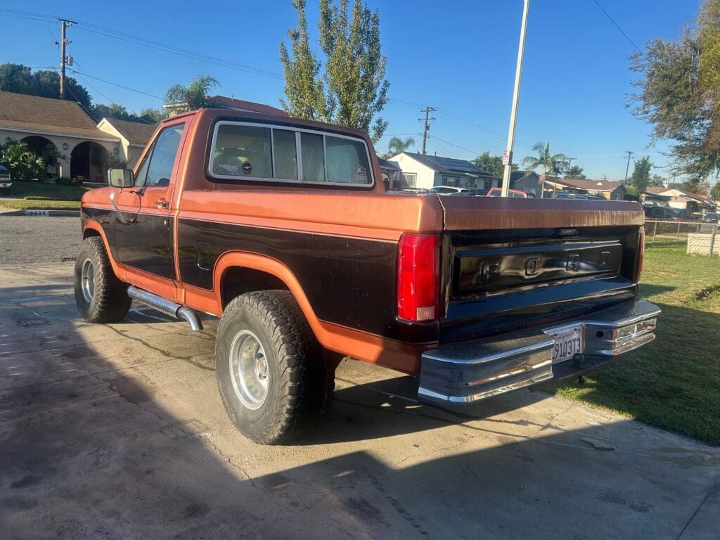 Classic black and orange vintage pickup truck parked outdoors.