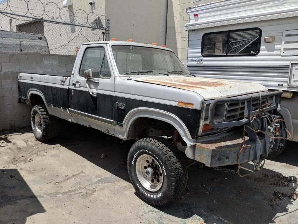 Old pickup truck with rust and wear parked in a driveway.