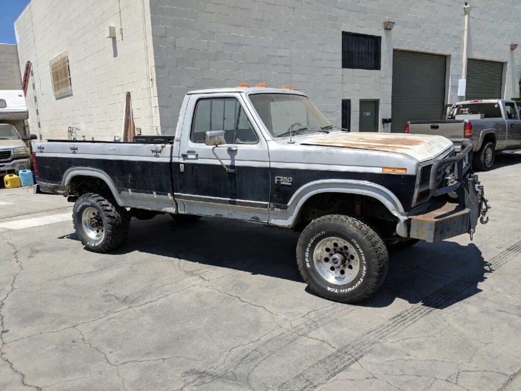 Old pickup truck with rust and wear parked in a driveway.