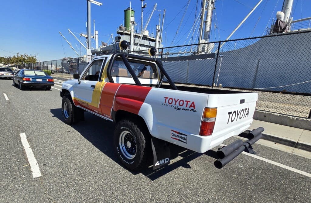 Classic Toyota pickup truck with a colorful red, yellow, and white paint job.