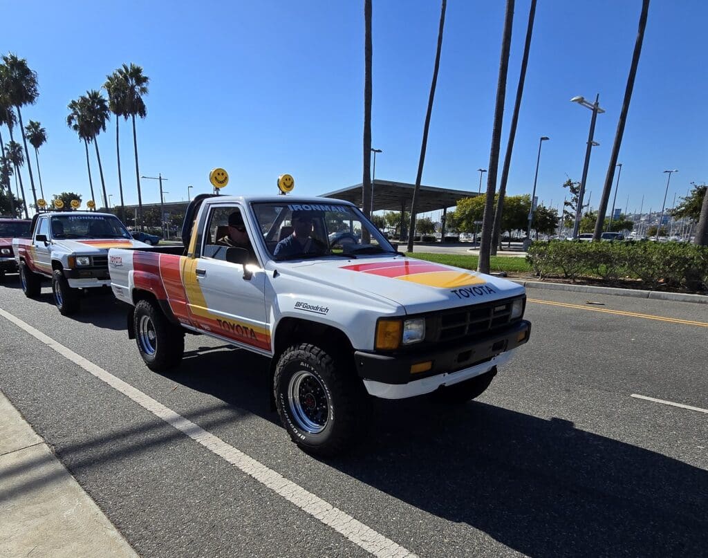 Vintage pickup truck parked under palm trees on a sunny day.