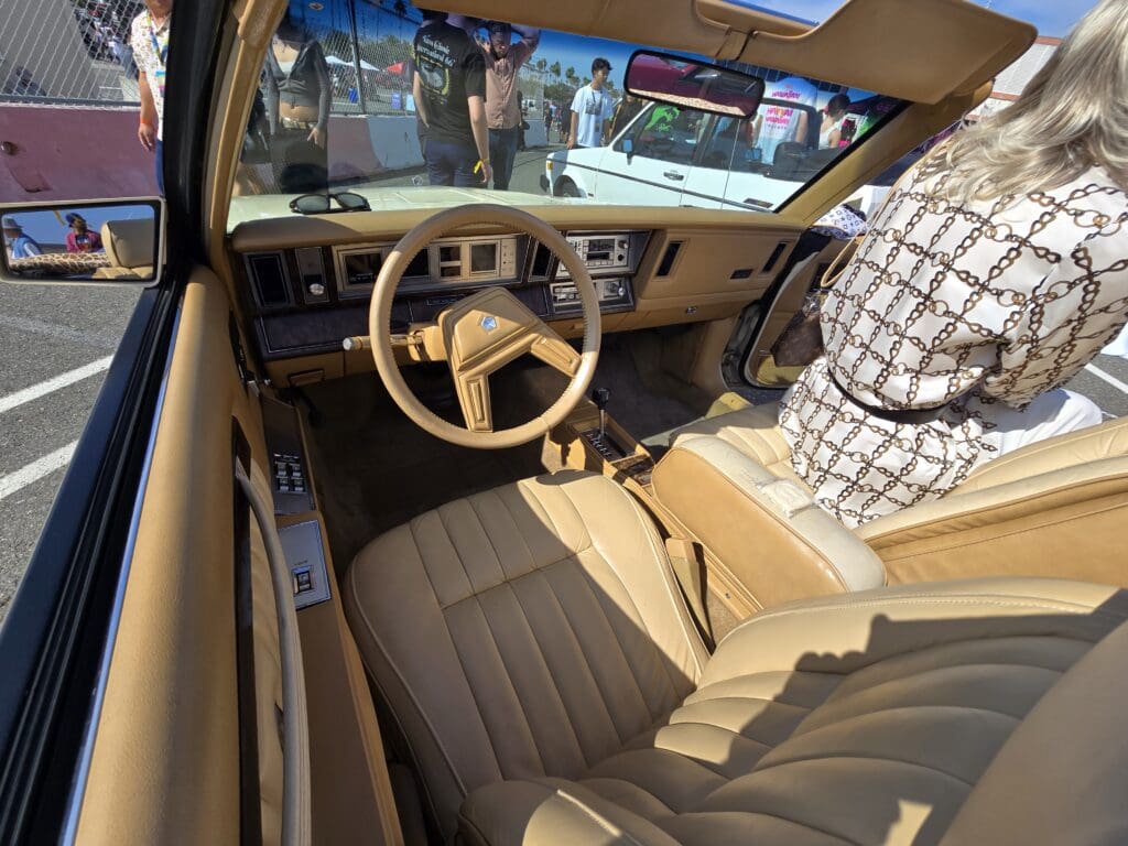 Interior of a vintage car with tan seats and steering wheel.