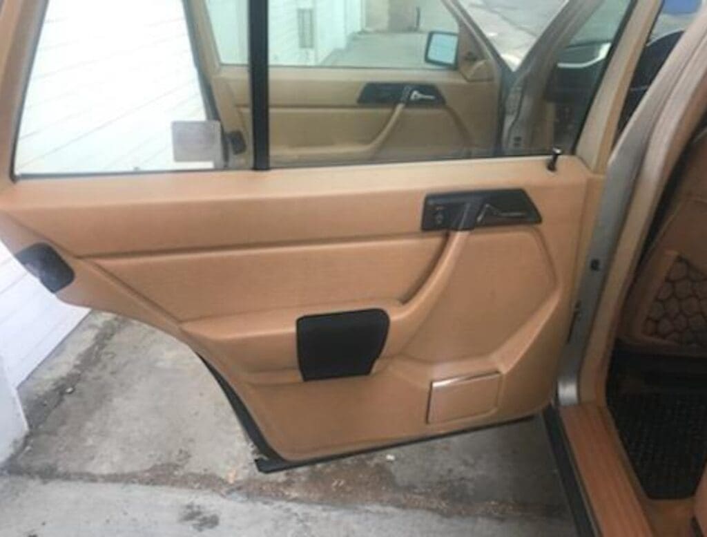 Open tan car door showing interior panel and window.