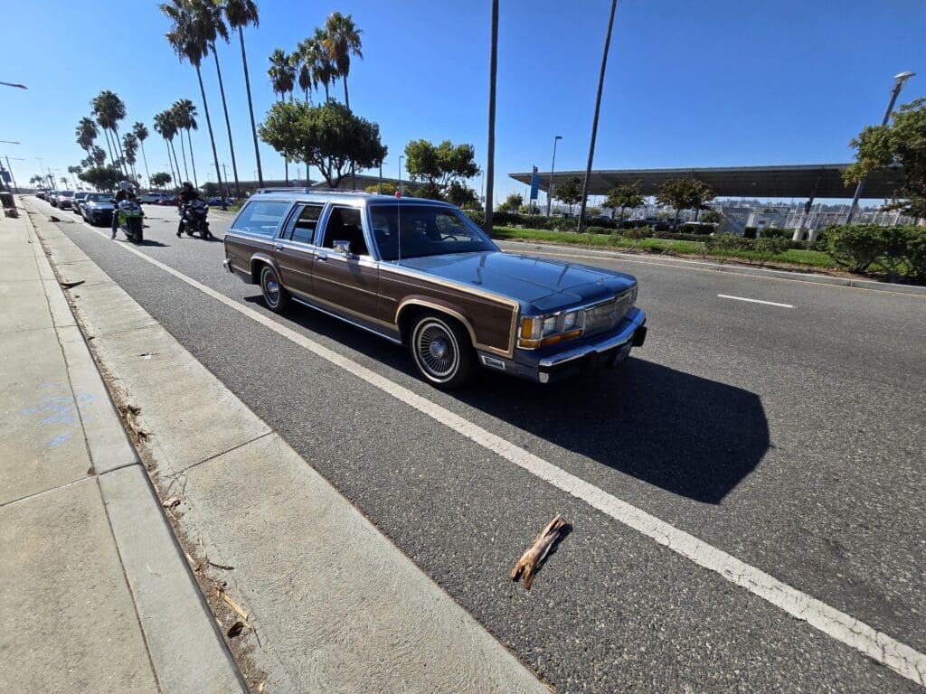 Classic wood-paneled station wagon parked by the seaside on a sunny day.