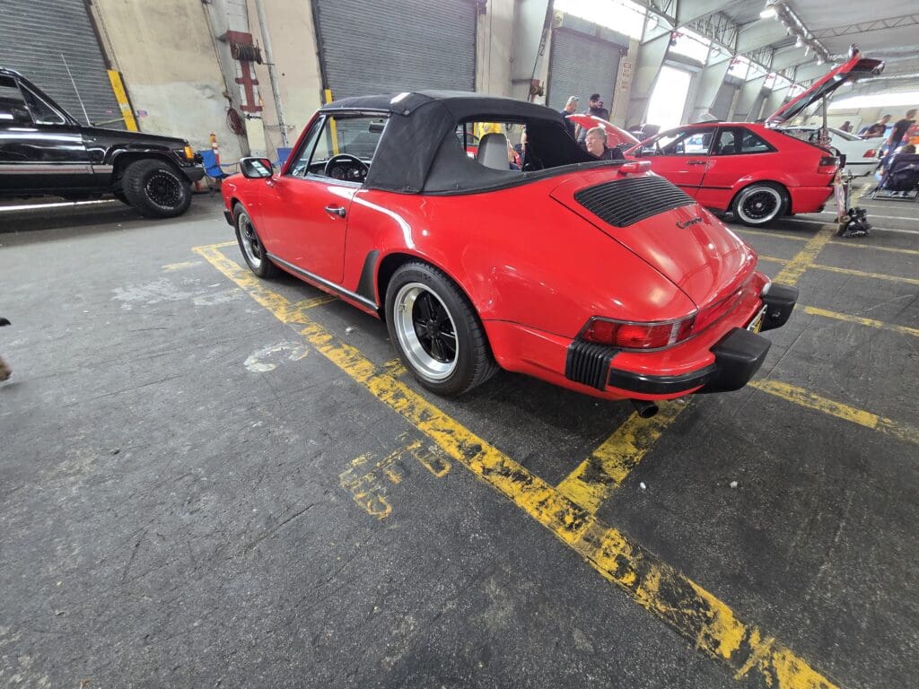 Red classic Porsche convertible parked indoors.