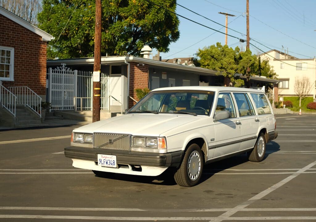 A vintage white station wagon parked in an outdoor lot on a sunny day.
