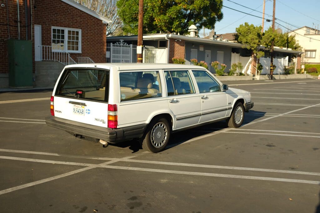 A vintage white station wagon parked in an outdoor lot on a sunny day.