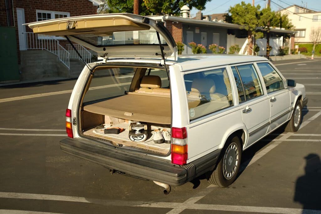 A station wagon with its rear hatch open showing a wooden storage setup.