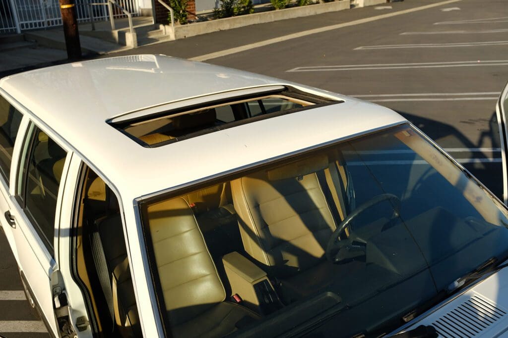 White car with an open sunroof parked on the street.