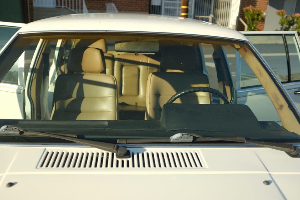 Interior view of a car showing seats and steering wheel through the windshield.