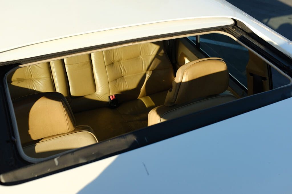 View of the beige leather car interior through the rear window.