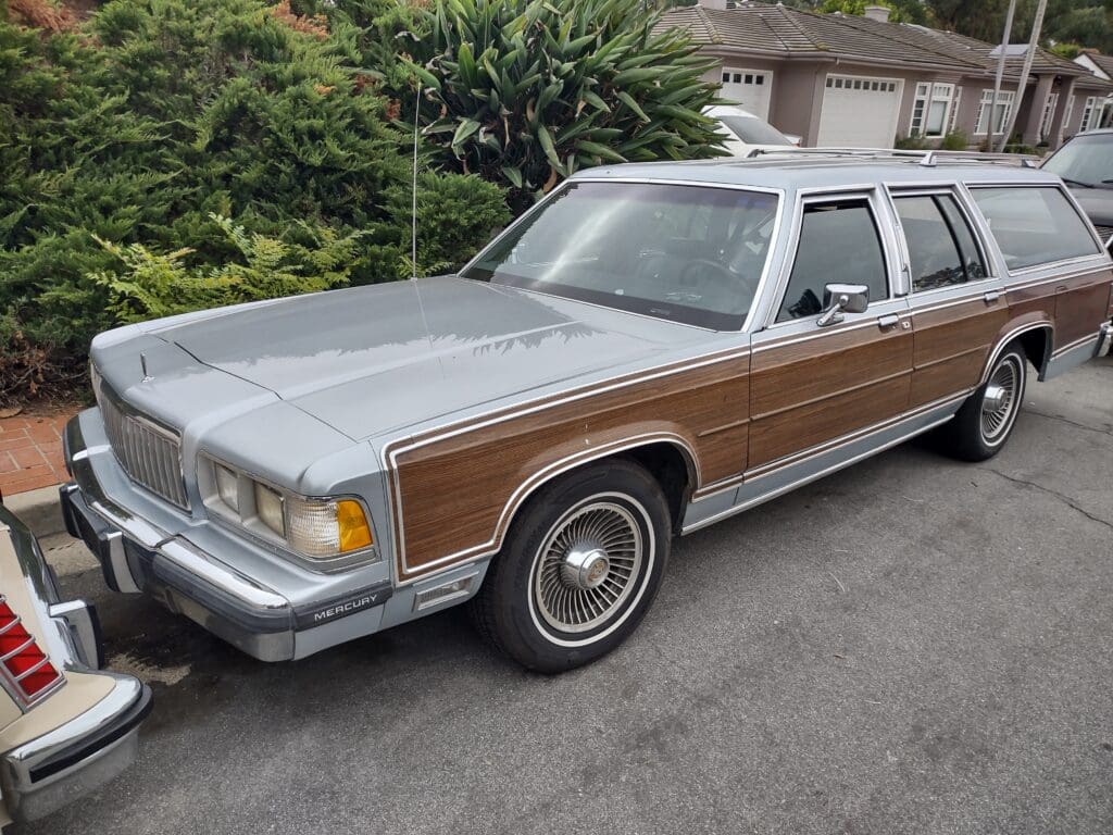 Classic silver station wagon with wood paneling parked on a residential street.