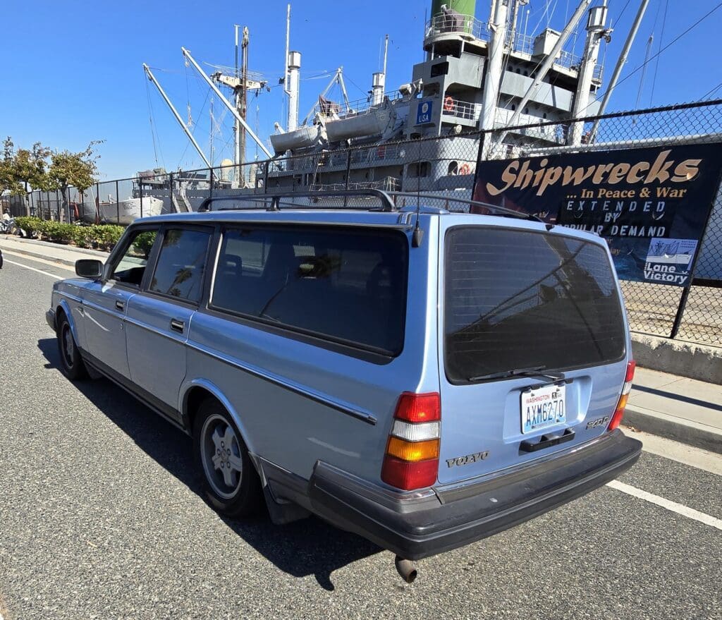 A vintage silver station wagon parked near a historic shipwreck museum.