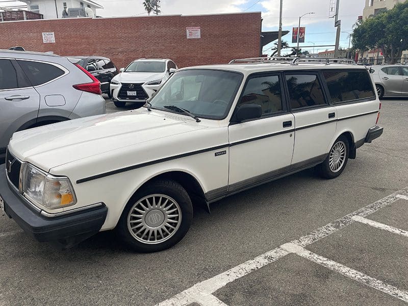 White vintage Volvo station wagon parked in a lot.