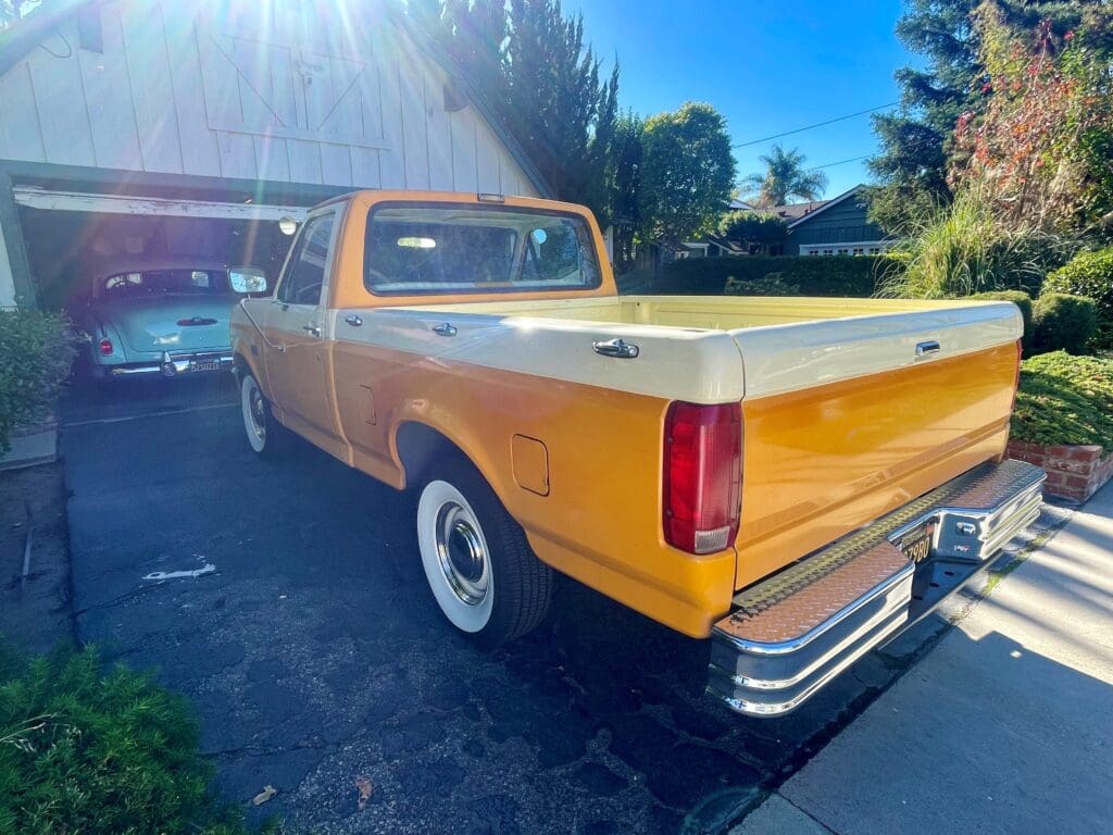 Classic yellow pickup truck parked outdoors on a sunny day.