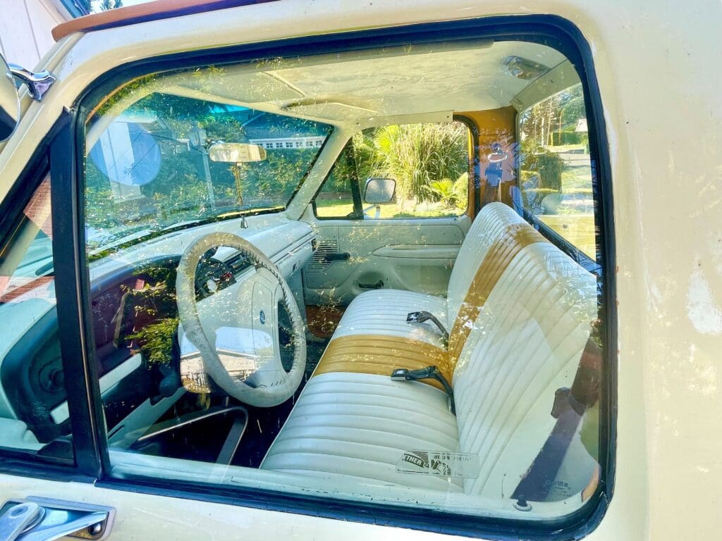 Classic car interior with white seats and vintage steering wheel.
