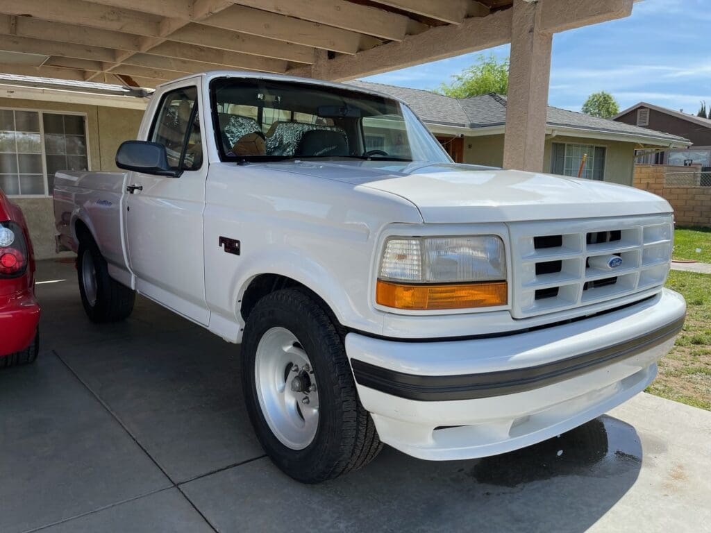 White Ford pickup truck parked under a carport.