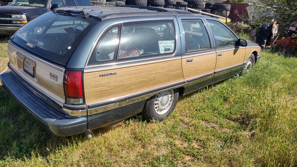A vintage station wagon with wood paneling parked on grass.