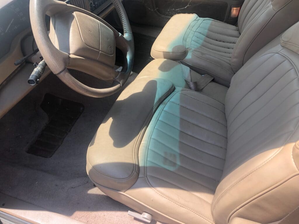 Close-up of beige car interior with fabric seats and steering wheel.