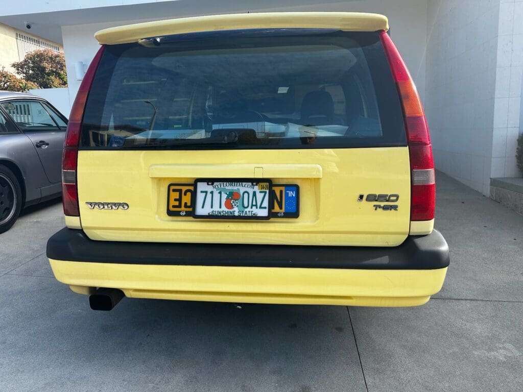 Yellow Volvo 240 station wagon with a colorful California license plate.