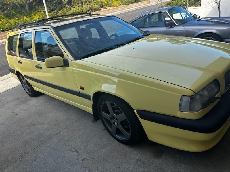 Yellow vintage car parked outdoors with black rims.