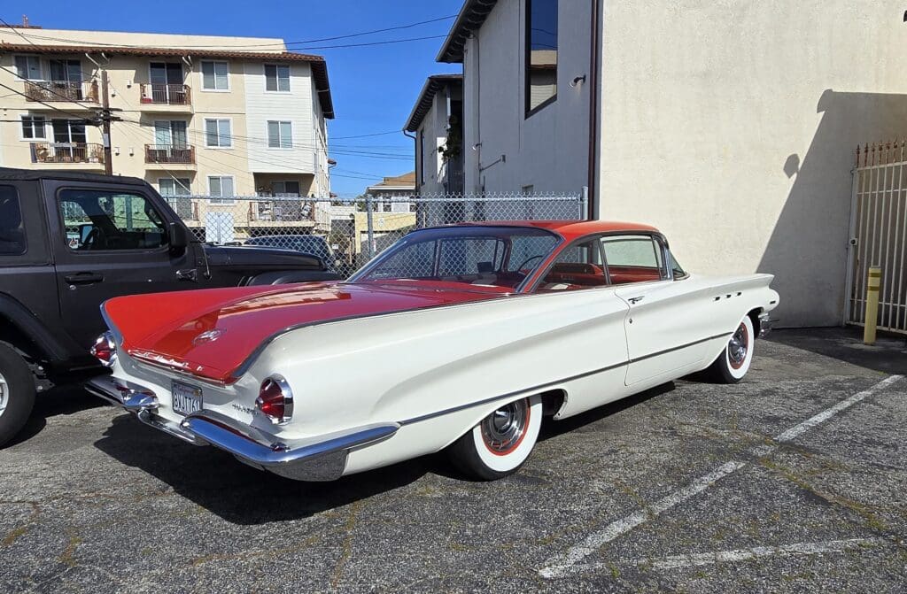 Classic red and white vintage convertible parked outdoors under a clear sky.