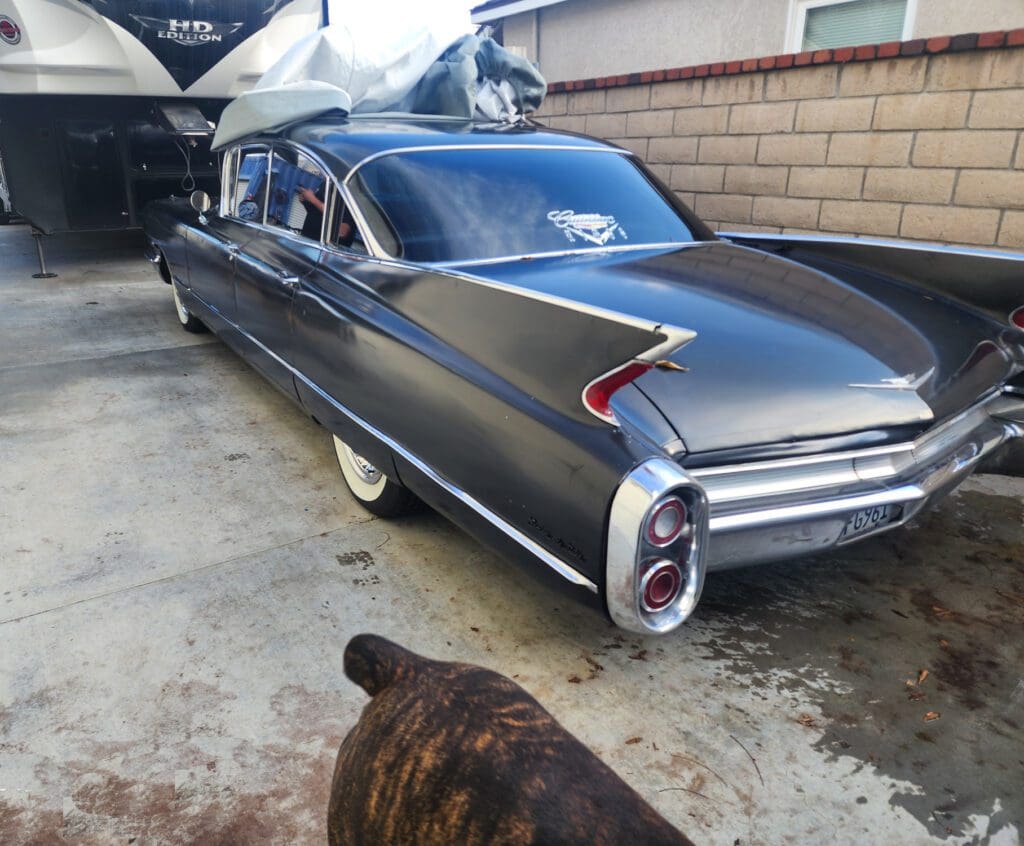 Classic black vintage car with whitewall tires parked on a driveway.