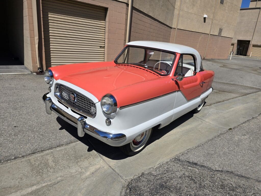 A vintage red and white convertible car parked on a street.