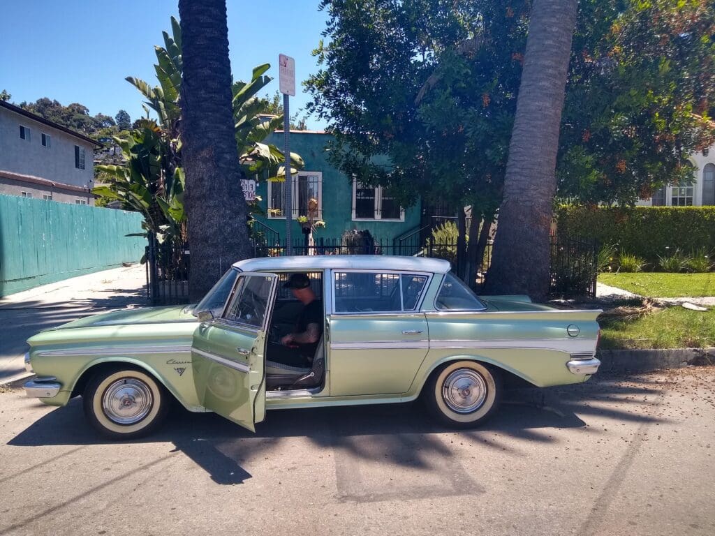 Classic vintage car parked near palm trees on a sunny day.