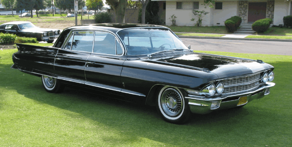 Classic black vintage car parked on grass beside a house.