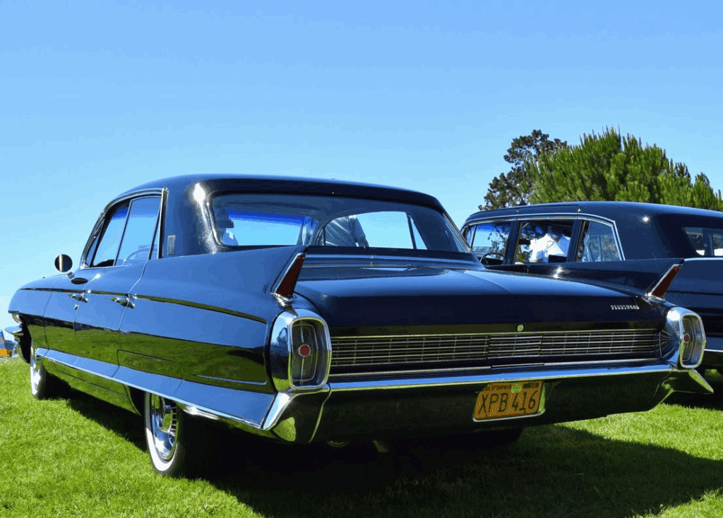 A classic black vintage car parked on green grass under a clear blue sky.