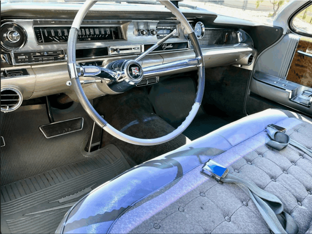 Interior of a vintage car with a classic steering wheel and blue upholstery.