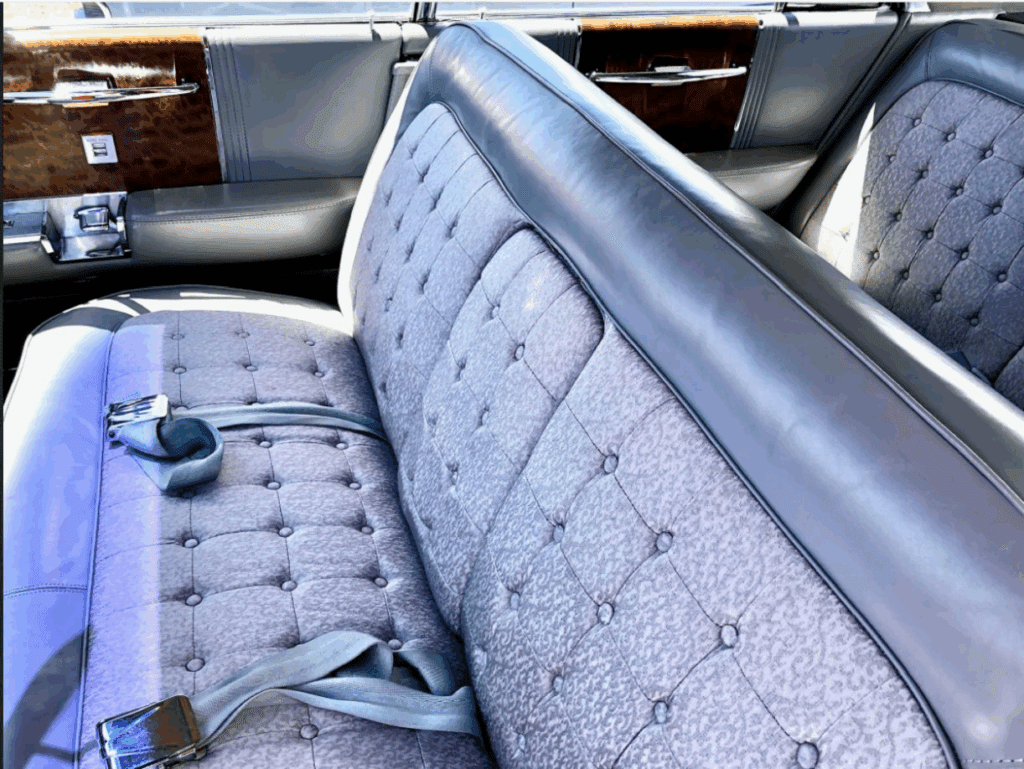 Close-up of vintage car's tufted leather bench seat and seatbelt.