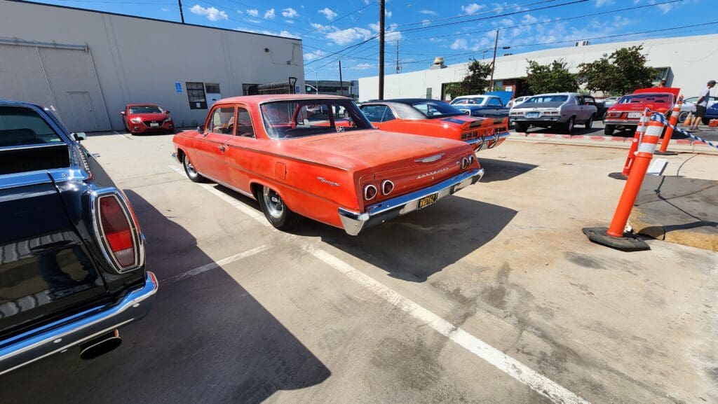 Classic red vintage car parked in a sunny lot.