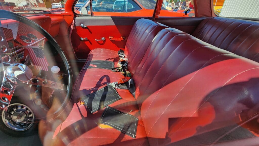 Interior of a vintage red car with leather seats and manual controls.