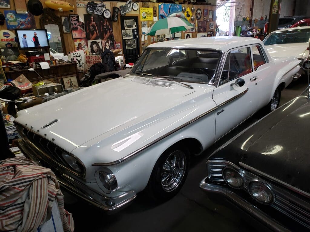 Classic white vintage car in a cluttered garage.