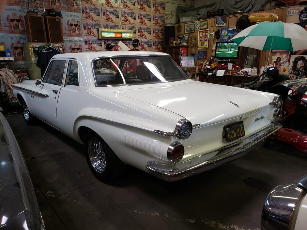 Classic white vintage car parked indoors with distinctive tail lights.