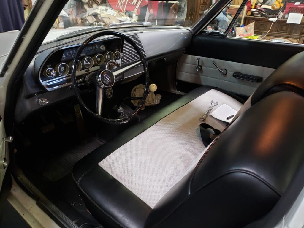 Interior of a vintage car showing the steering wheel and bench seat.
